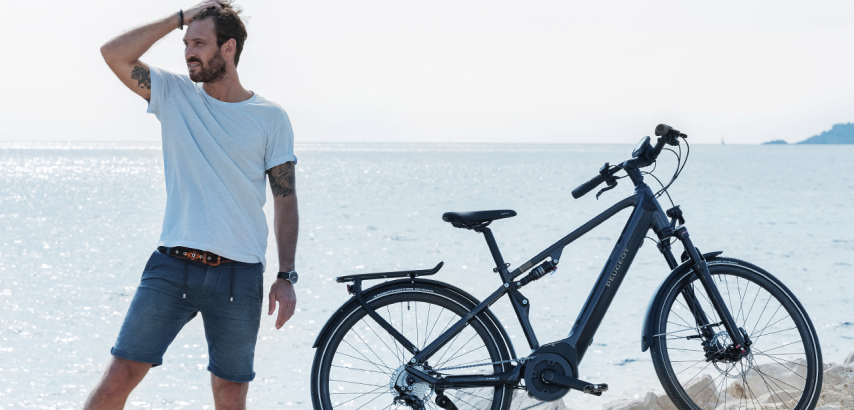 Hombre de espaldas al mar y junto a su bicicleta
